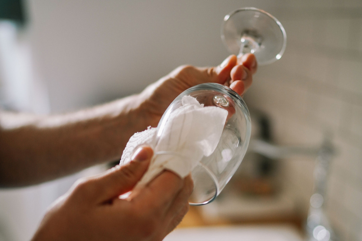 Person reinigt ein Weinglas mit einem weißen Tuch
