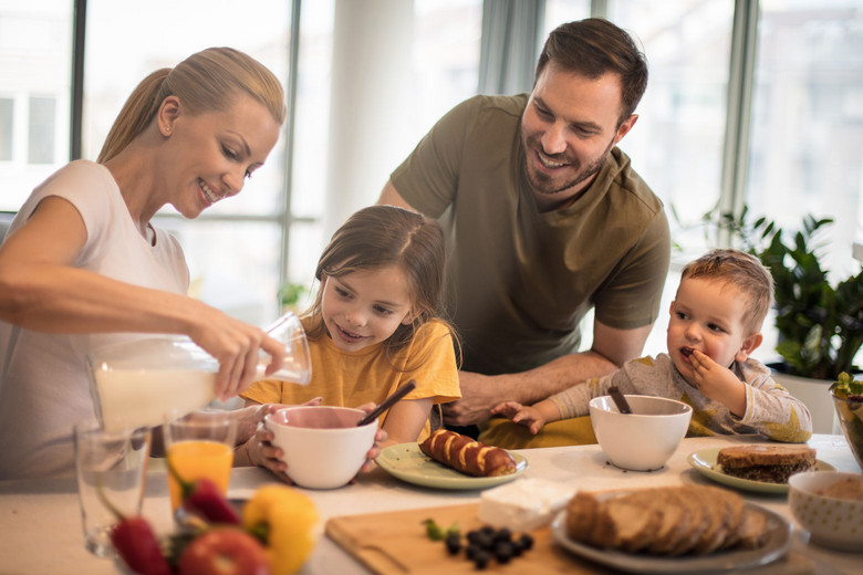 Eine junge Familie frühstückt an einem reichlich gedeckten Tisch