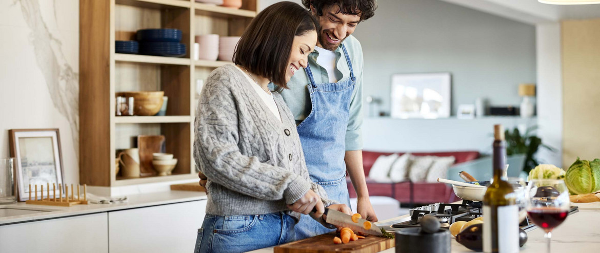 Eine Frau und ein Mann schneiden Gemüse auf einer Anrichte in der Küche