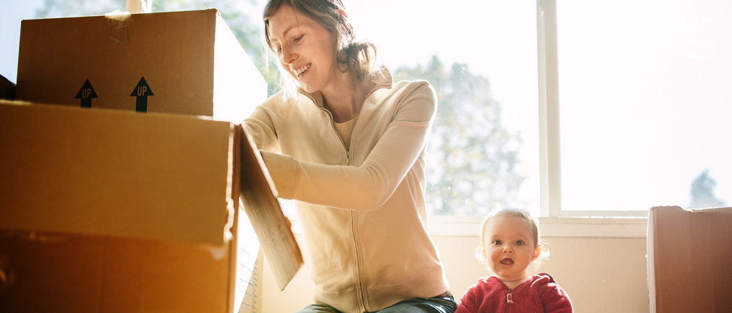 Mutter und Kind packen Umzugskarton.