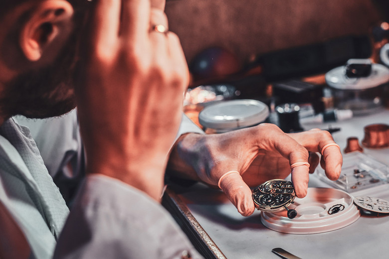 Eine Mann schaut sich eine Uhr in einer Uhrenwerkstatt genau an