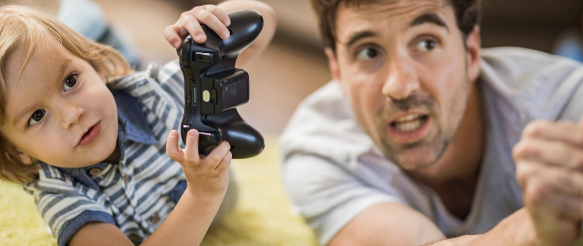 Ein Vater und seine Tochter spielen mit einer PlayStation 2