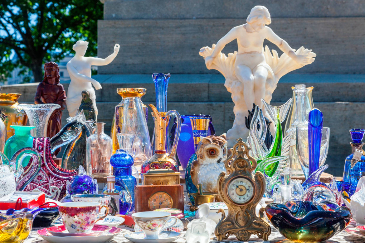 Ein Tisch auf dem Trödelmarkt mit Antiquitäten und Figuren