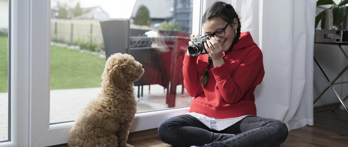 Ein Mädchen mit einer Kamera vor einem Hund