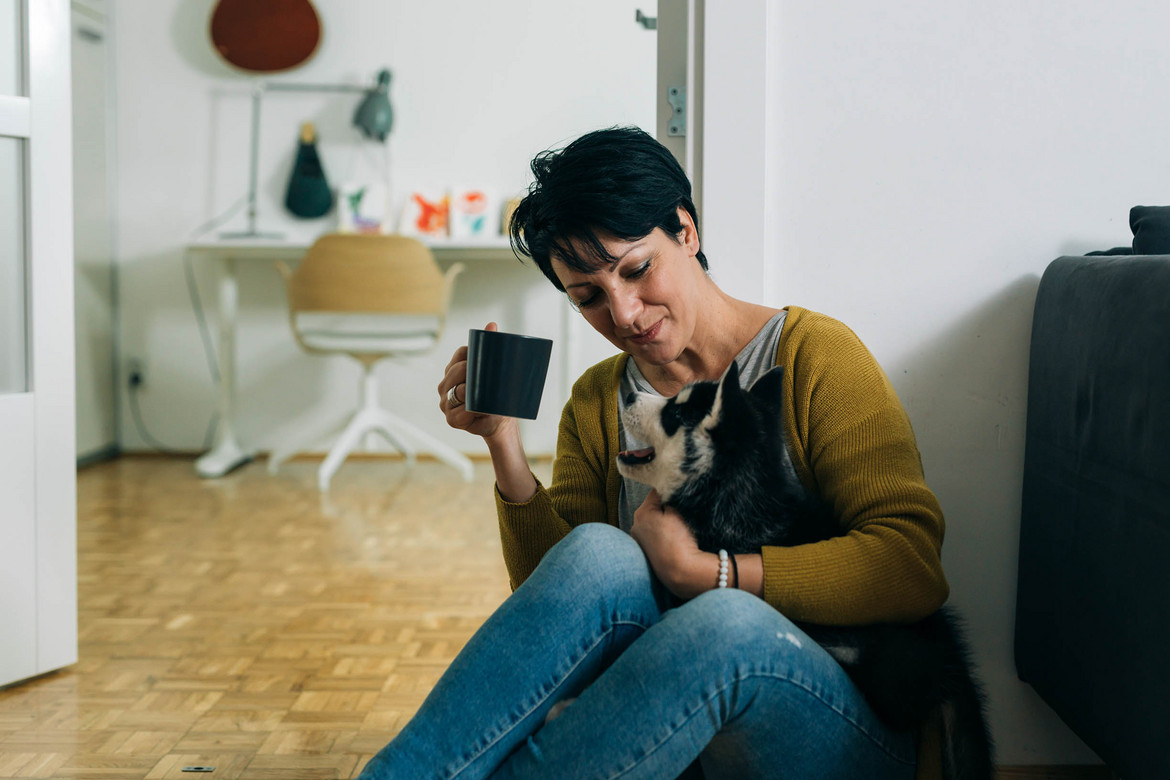 Ein Bild einer auf dem Boden sitzenden Frau in einer Wohnung mit Hund