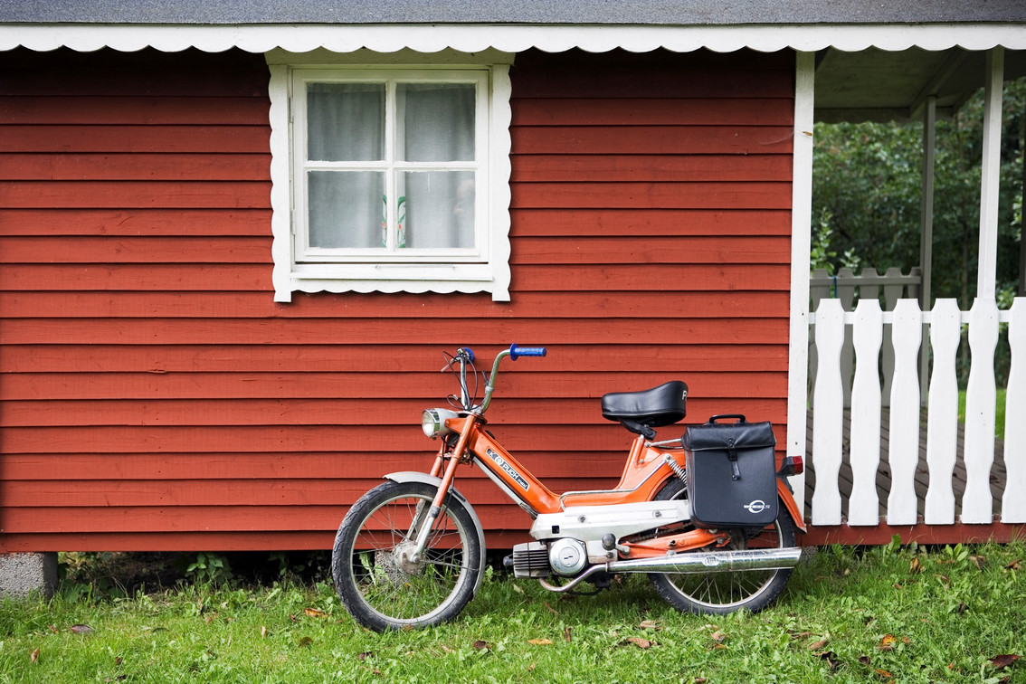 Ein Bild eines Mopeds vor einem Holzhaus